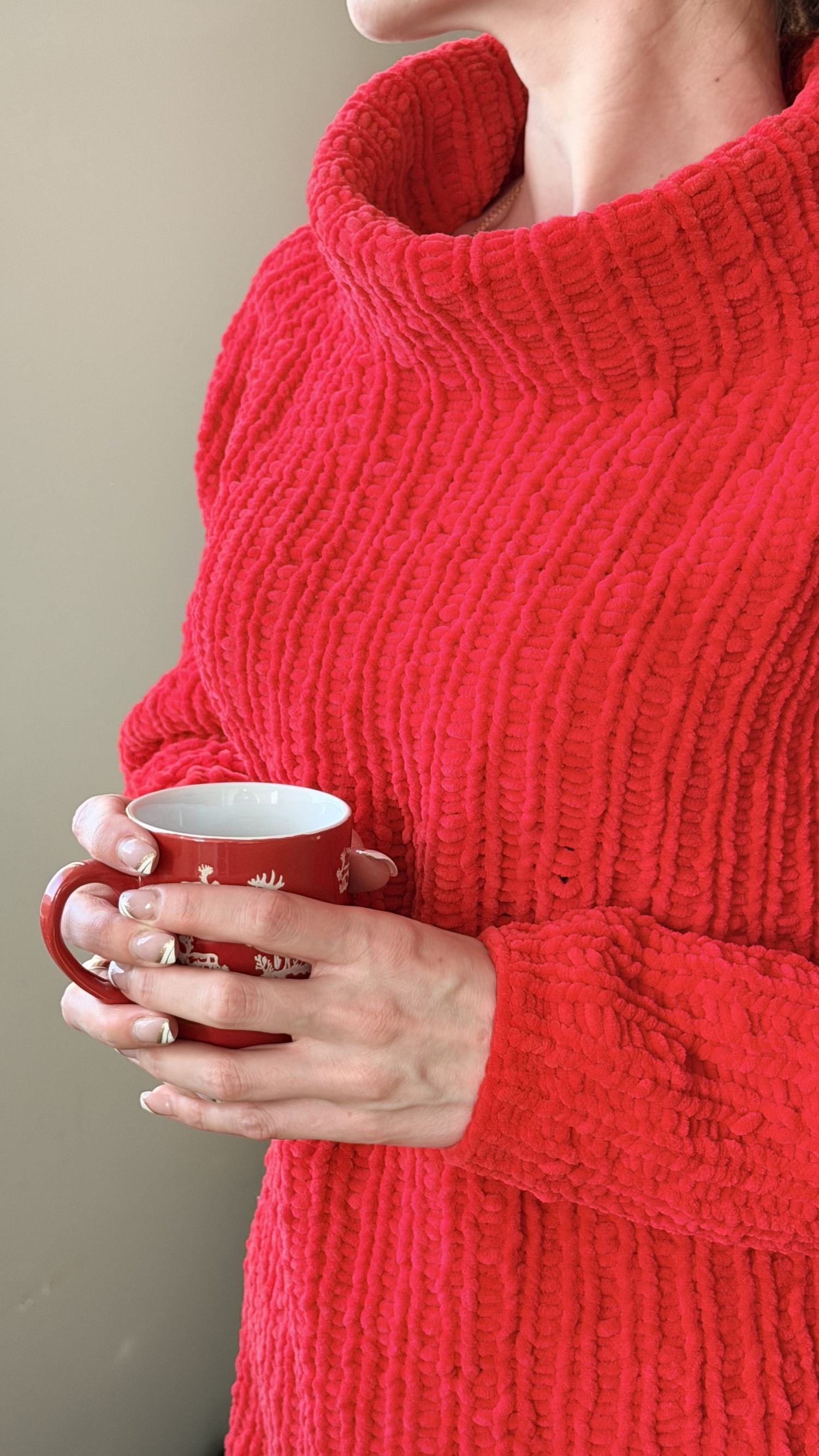 A plush red turtleneck sweater, worn with a cup of coffee